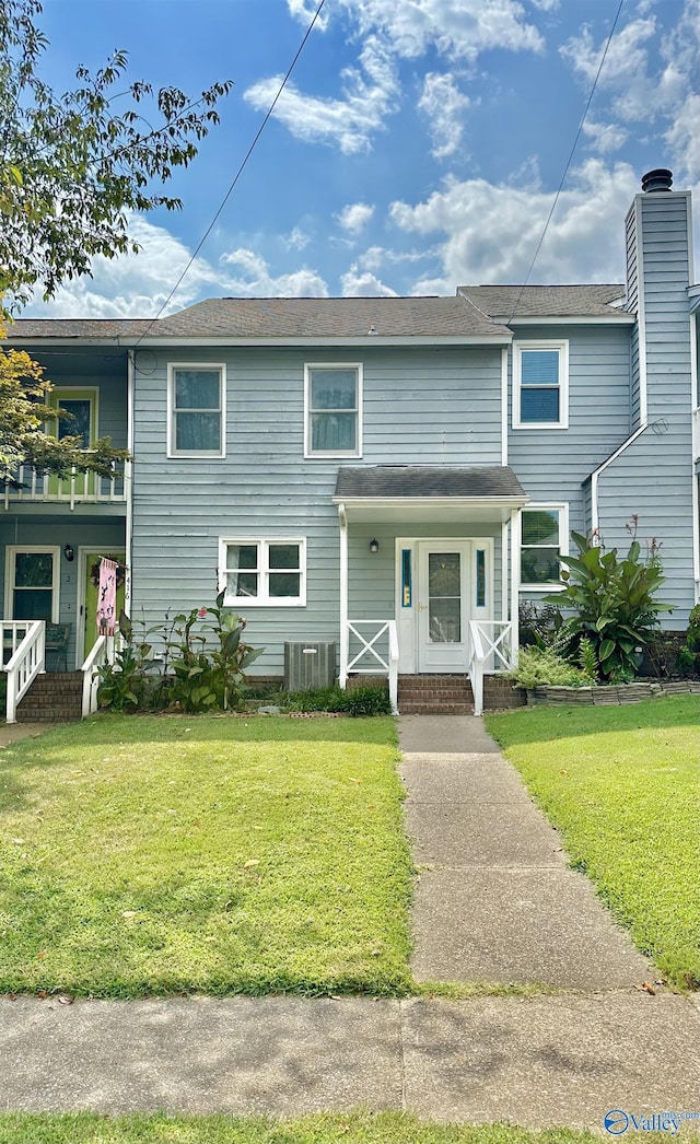 townhome / multi-family property with a front yard, a chimney, and a balcony