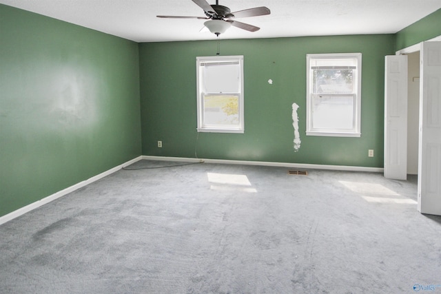 carpeted empty room with visible vents, ceiling fan, and baseboards