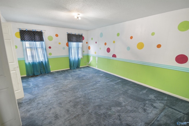 carpeted empty room featuring a textured ceiling and baseboards