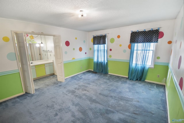 carpeted empty room with a textured ceiling and baseboards