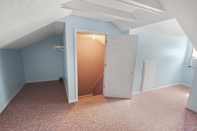 additional living space featuring a textured ceiling, carpet floors, vaulted ceiling, and baseboards