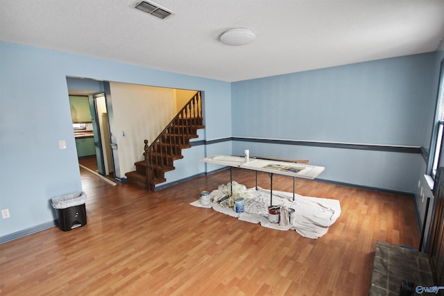 interior space with stairs, wood finished floors, visible vents, and baseboards