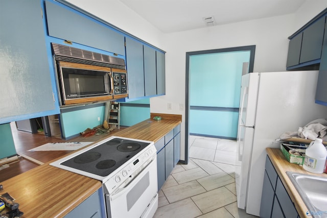 kitchen with white appliances, visible vents, light countertops, blue cabinetry, and a sink