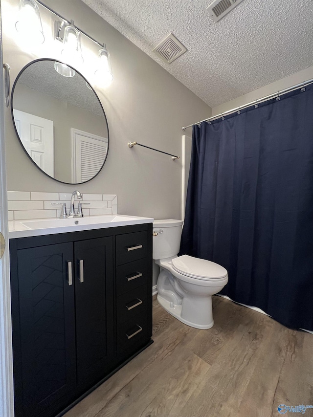 bathroom featuring wood-type flooring, a textured ceiling, toilet, decorative backsplash, and vanity