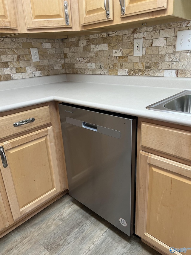 kitchen featuring backsplash, light brown cabinetry, stainless steel dishwasher, and light wood-type flooring