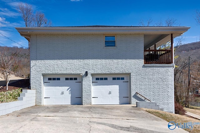 exterior space featuring concrete driveway, brick siding, and an attached garage