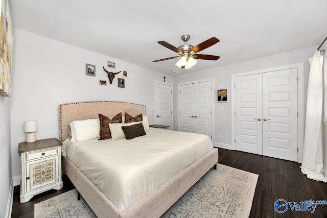 bedroom with ceiling fan, baseboards, dark wood finished floors, and two closets