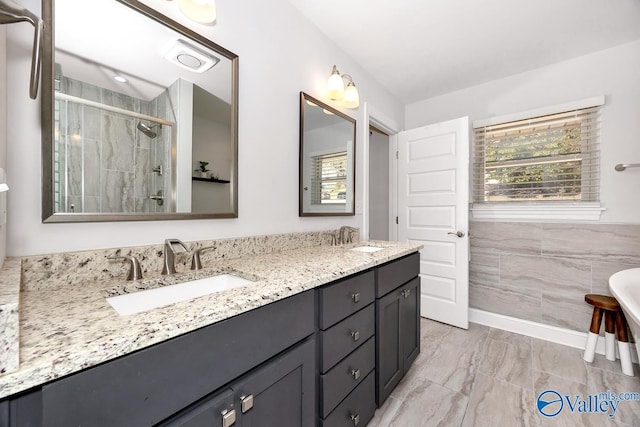 bathroom with double vanity, a stall shower, marble finish floor, and a sink