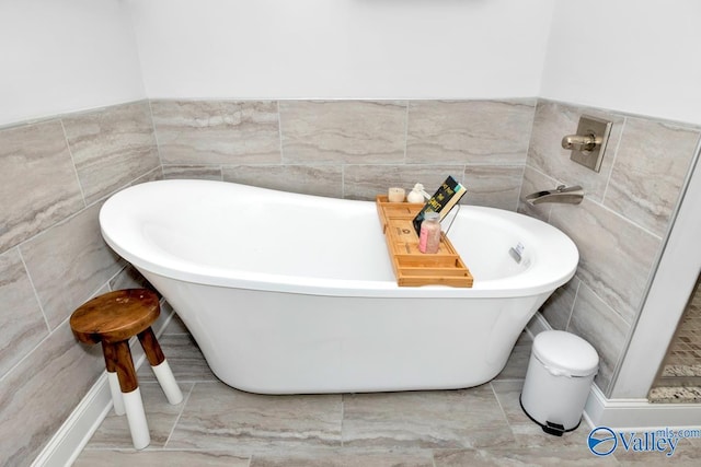 bathroom with a freestanding tub and tile walls