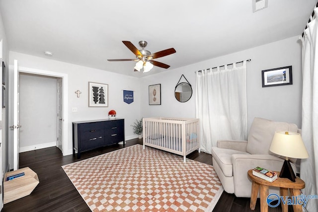 bedroom featuring dark wood-type flooring, a ceiling fan, visible vents, and baseboards