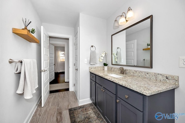 bathroom featuring vanity, baseboards, and wood finished floors