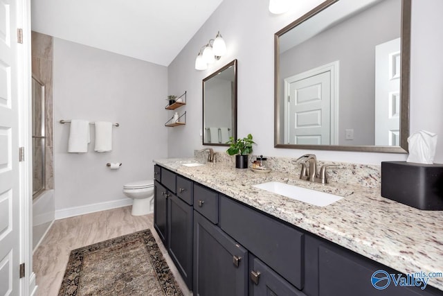 bathroom with double vanity, a sink, toilet, and baseboards