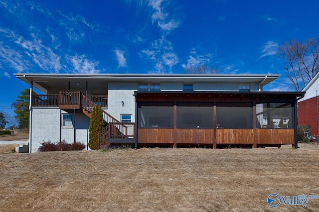 back of property with a sunroom, brick siding, and stairway