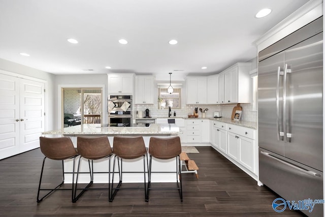 kitchen featuring appliances with stainless steel finishes, a center island, white cabinets, and plenty of natural light