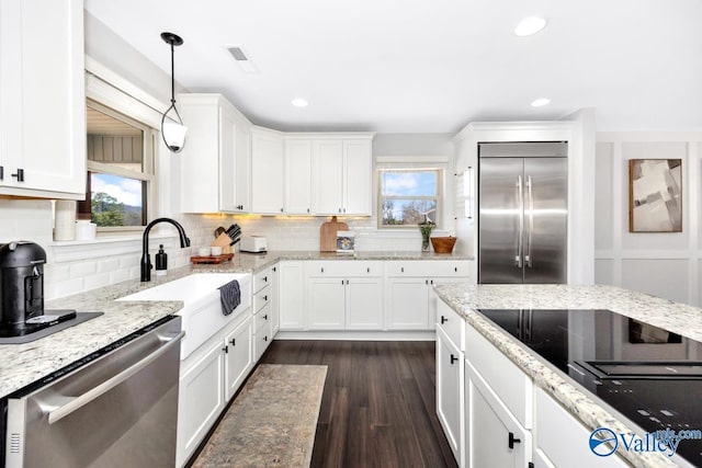 kitchen with stainless steel appliances, a healthy amount of sunlight, white cabinets, and a sink