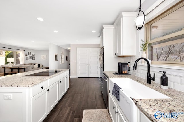 kitchen featuring white cabinets, dark wood-type flooring, a kitchen island with sink, black electric stovetop, and recessed lighting