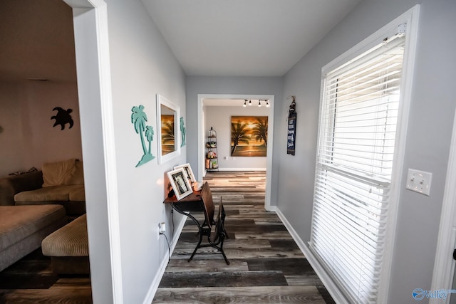 hall with dark wood-style flooring and baseboards