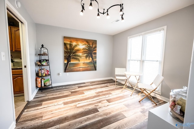 living area with baseboards, visible vents, a notable chandelier, and light wood-type flooring