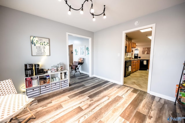 living area featuring baseboards, an inviting chandelier, and light wood-style floors
