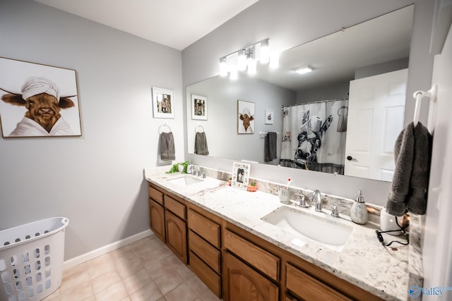 full bath featuring double vanity, tile patterned floors, baseboards, and a sink