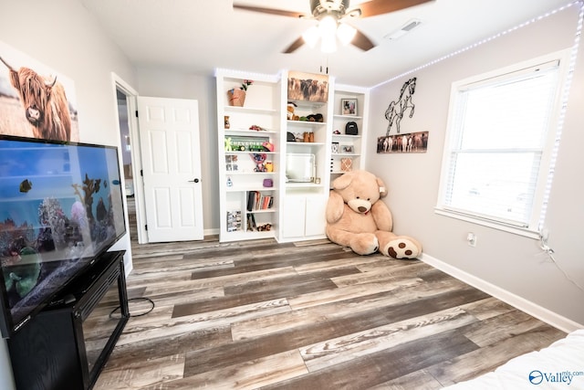 recreation room featuring a ceiling fan, visible vents, wood finished floors, and baseboards