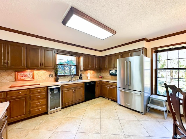 kitchen with light countertops, wine cooler, a sink, freestanding refrigerator, and black dishwasher