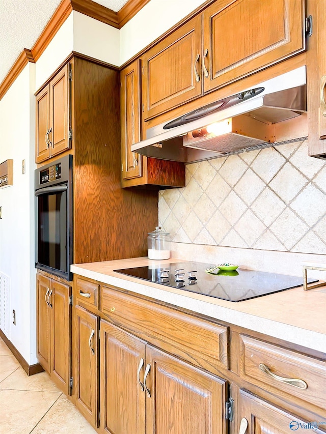 kitchen featuring light countertops, backsplash, black electric cooktop, under cabinet range hood, and wall oven