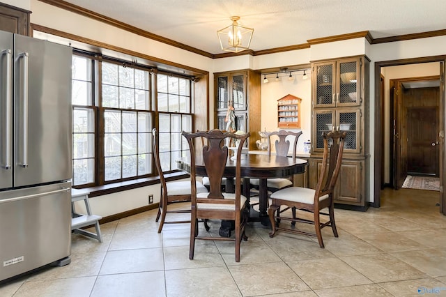 dining area featuring crown molding, a chandelier, a textured ceiling, light tile patterned floors, and baseboards