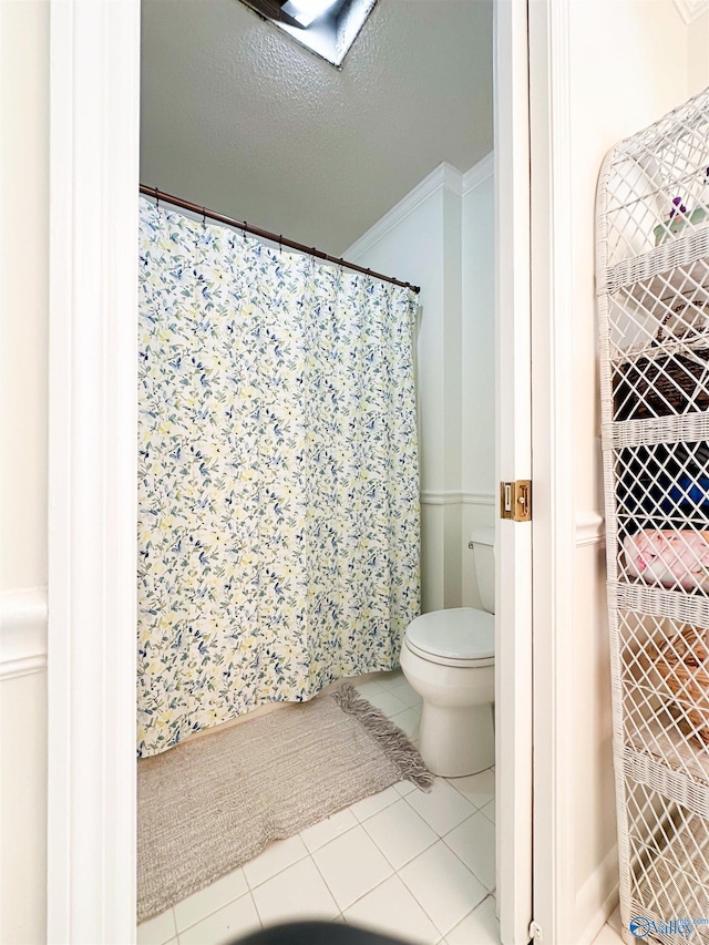 full bathroom featuring tile patterned floors, crown molding, toilet, and a textured ceiling