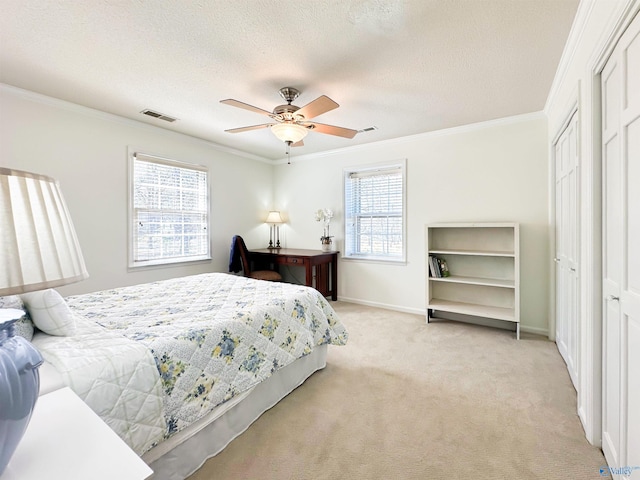 bedroom featuring light colored carpet, ornamental molding, baseboards, a textured ceiling, and visible vents