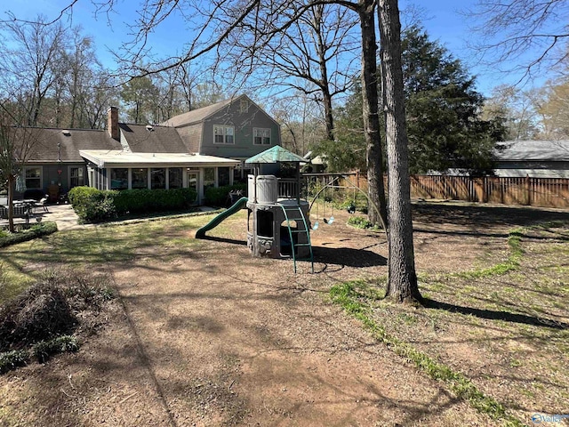 view of yard featuring a sunroom, fence, and a playground