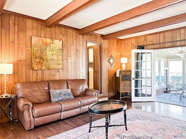 living area featuring beam ceiling, a ceiling fan, wood finished floors, wood walls, and washer / clothes dryer