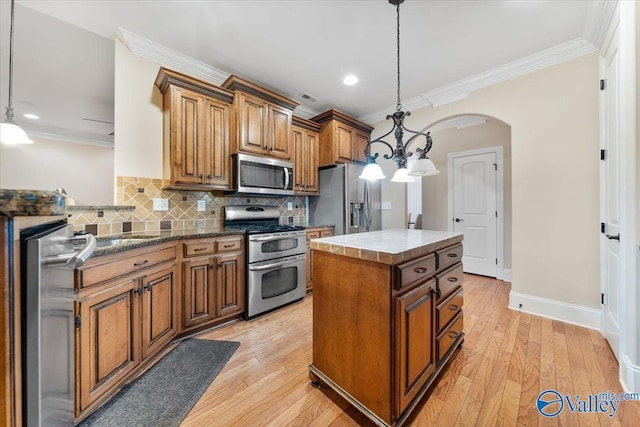 kitchen with stainless steel appliances, a center island, decorative light fixtures, ornamental molding, and decorative backsplash