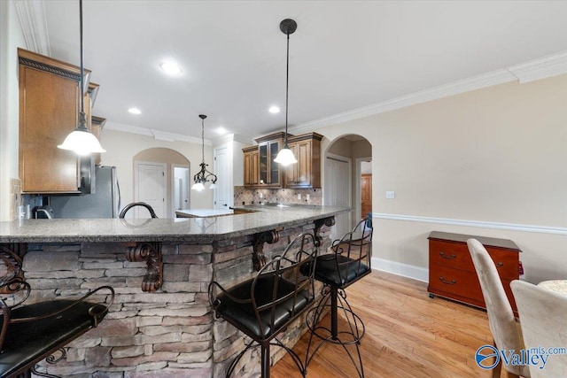 kitchen with decorative backsplash, pendant lighting, a kitchen bar, and kitchen peninsula