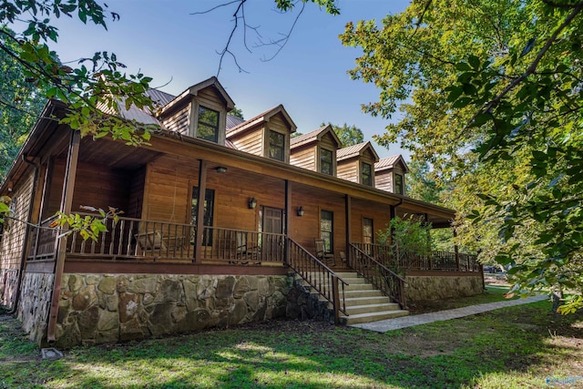 view of front of house with covered porch, stairs, and a front lawn