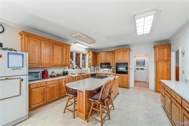 kitchen with a kitchen breakfast bar, black appliances, crown molding, a center island, and sink