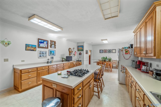 kitchen with ornamental molding, stainless steel gas cooktop, a textured ceiling, and white refrigerator