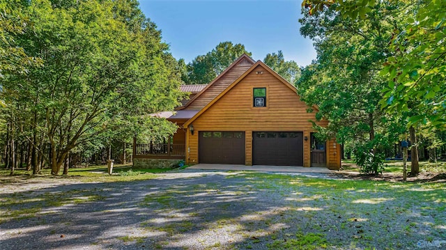 rustic home with driveway, a garage, and metal roof