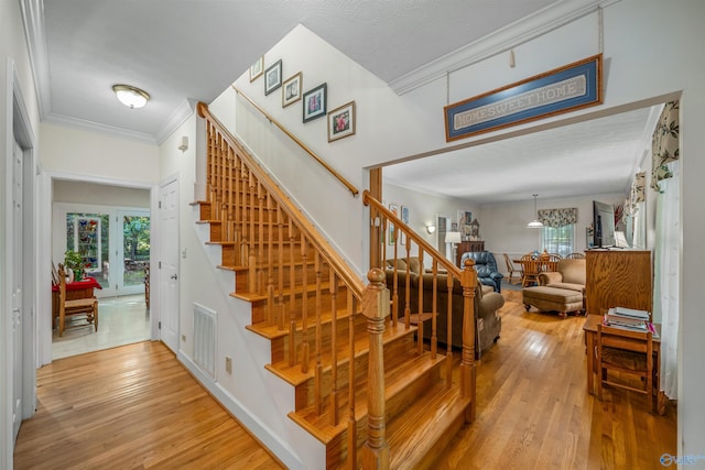 staircase with hardwood / wood-style flooring and crown molding