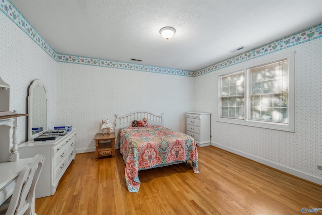 bedroom with light wood-type flooring and a textured ceiling