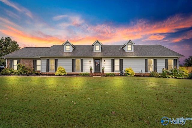 cape cod house featuring a lawn