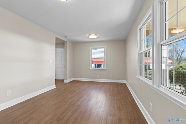unfurnished room with baseboards and dark wood finished floors