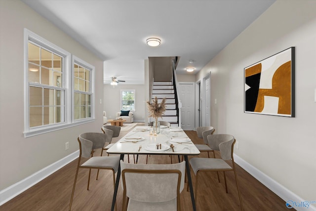 dining room featuring baseboards, wood finished floors, and stairs