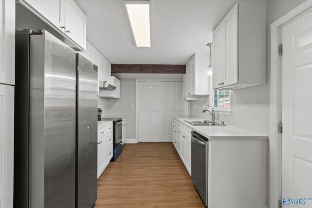 kitchen featuring stainless steel appliances, light countertops, a sink, and white cabinetry