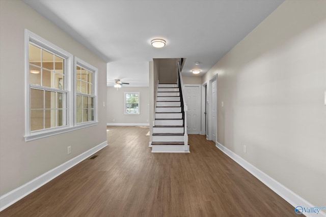 unfurnished living room featuring stairs, dark wood-type flooring, visible vents, and baseboards