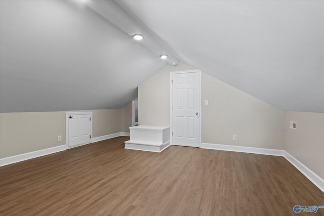 additional living space with wood finished floors, baseboards, and vaulted ceiling