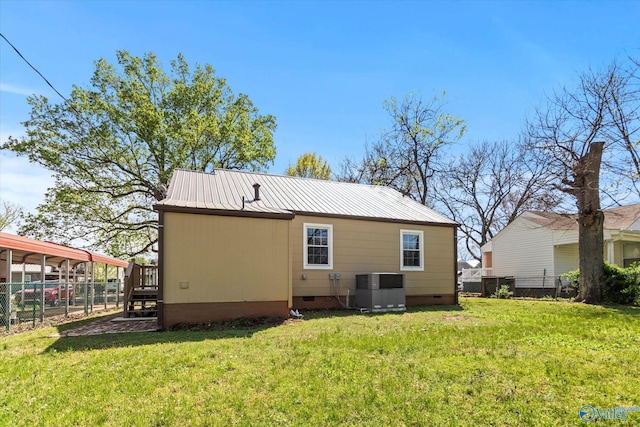 rear view of house with central AC, a yard, metal roof, crawl space, and fence