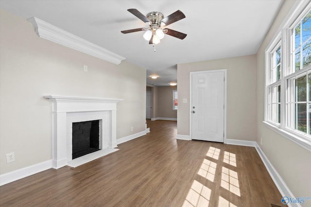 unfurnished living room featuring baseboards, ornamental molding, a fireplace, a ceiling fan, and wood finished floors
