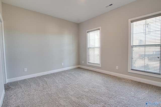 empty room featuring carpet flooring, visible vents, and baseboards