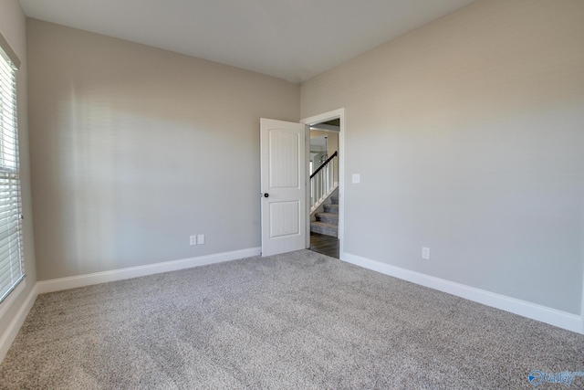 empty room featuring stairs, carpet flooring, and baseboards